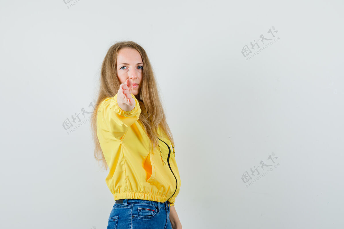 成人身穿黄色棒球服和蓝色牛仔裤的年轻女子 正眼望着镜头肖像女性正面