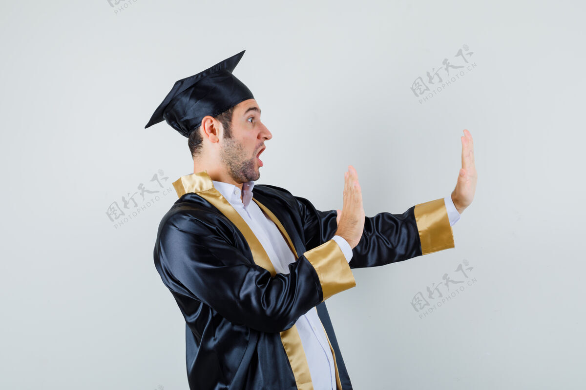 制服年轻人手挽手保护自己在研究生制服和看起来害怕毕业男人快乐
