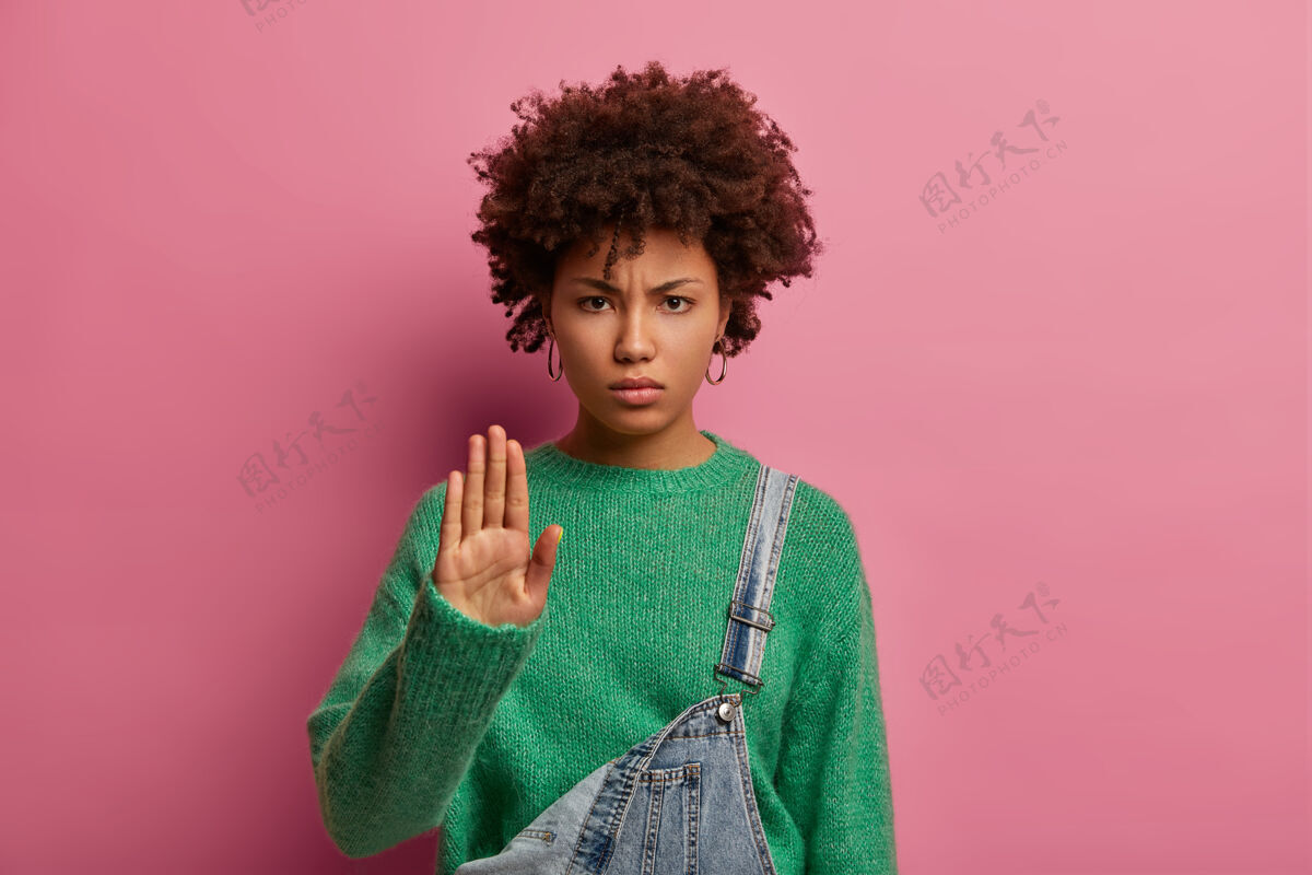 人严肃的卷发女青年照片拒绝陌生的提议 拉着手掌 拒绝求婚 神情不满 穿着绿色毛衣 警告不要再通过了女孩禁止举行