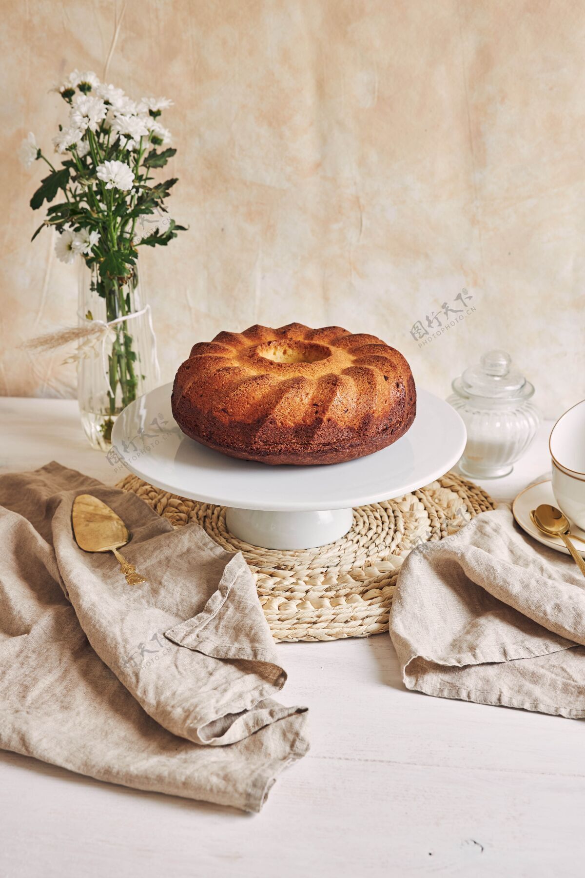 灯光美丽的镜头美味的环蛋糕放在一个白色的盘子和一个白色的花靠近它派鲜花美食