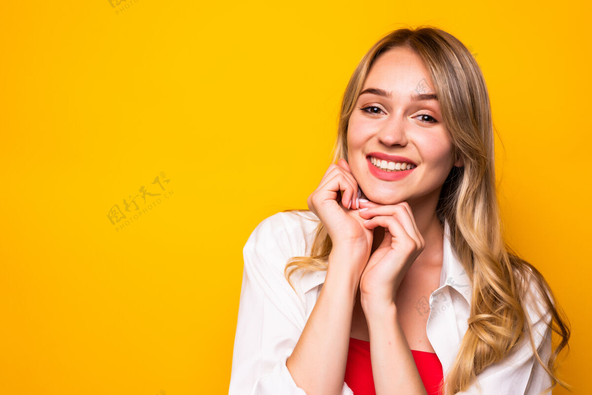 夏天美丽的年轻女子手拉着下巴 微笑着 站在黄色的墙上积极时尚粉彩