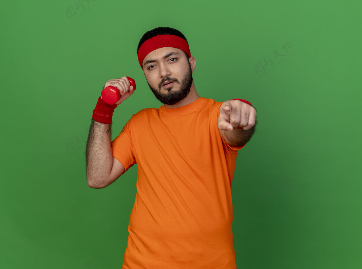 腕带自信的年轻运动型男子戴着头带和腕带 在绿色背景上练习哑铃 向你展示孤立的姿势手势自信锻炼