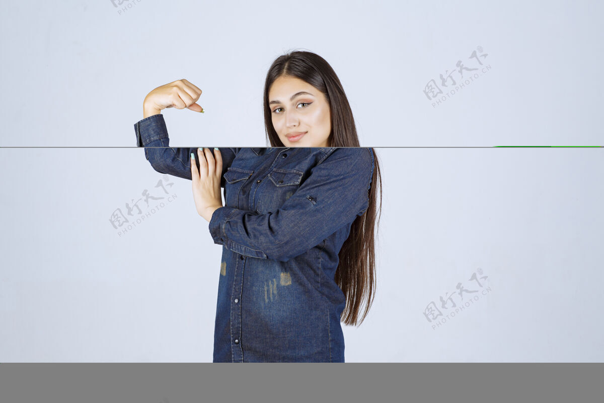 女性穿着牛仔衬衫的年轻女子展示了她的手臂肌肉拳头锻炼运动