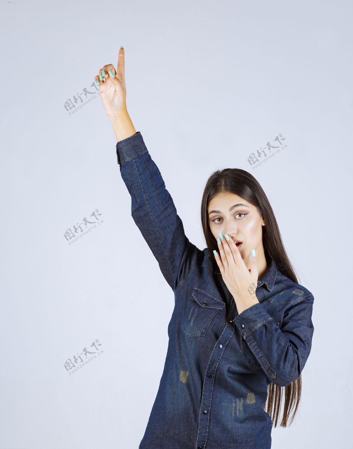 女人穿着牛仔衫的年轻女子举起双手 指着上面的东西上身人类模特