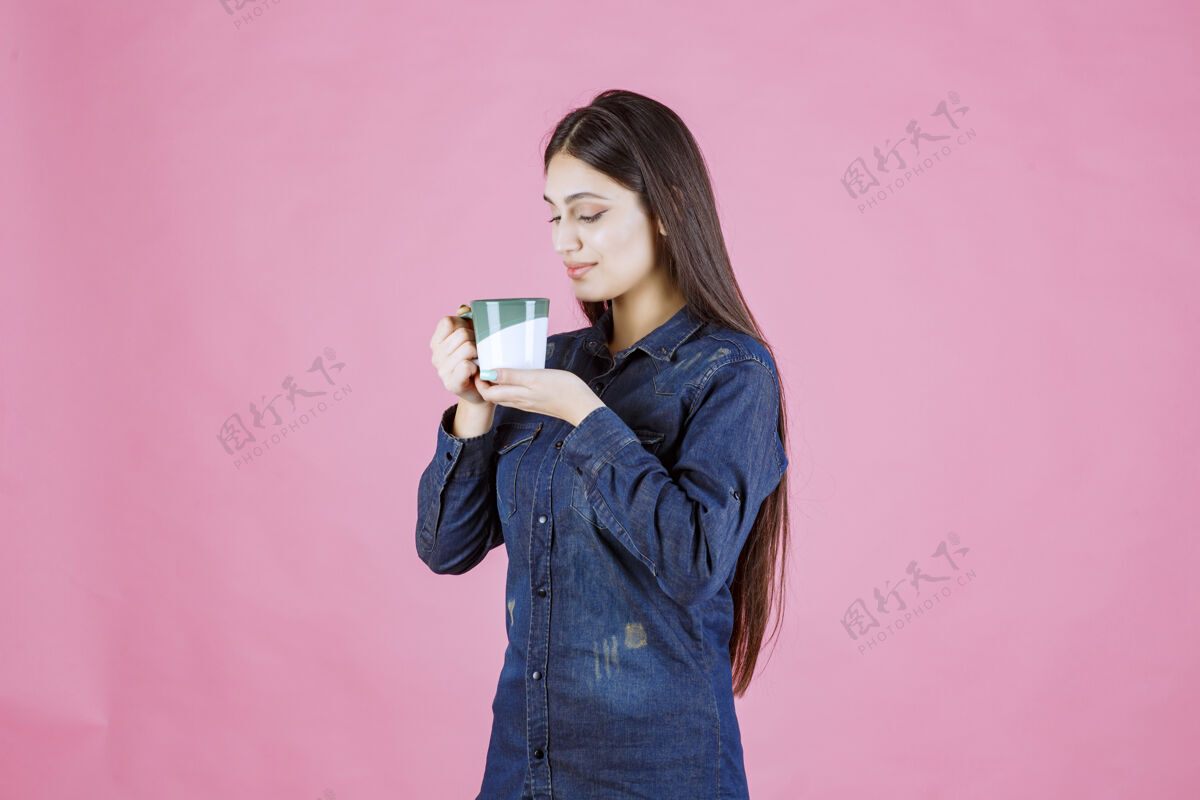 年轻人年轻女子拿着一个白绿色的咖啡杯 闻着工人聪明女人