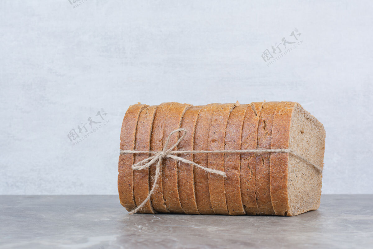 面包用绳子把棕色面包片放在大理石表面面包切健康