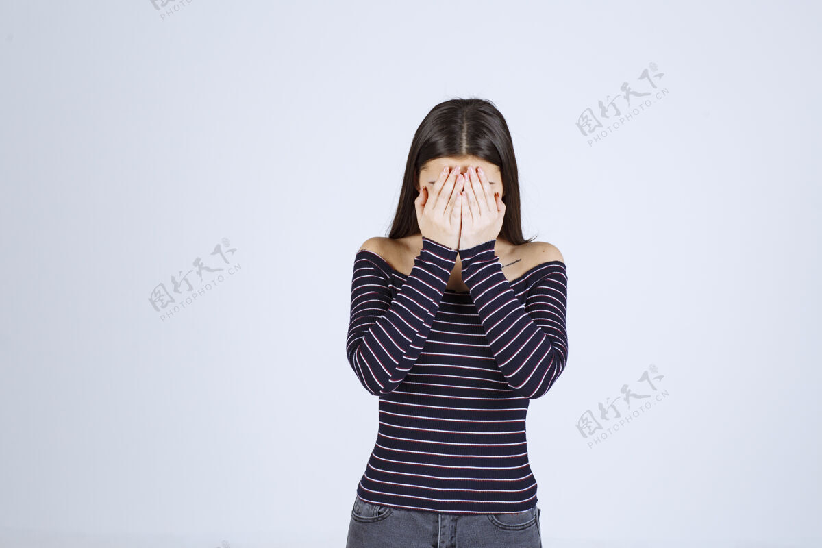 服装穿着条纹衬衫的女孩抱着她的头 因为她筋疲力尽或头痛年轻疾病无聊
