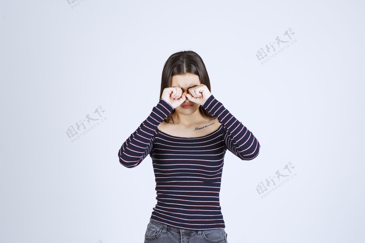 年轻人穿条纹衬衫的女孩透过手指看年轻姿势人体模特