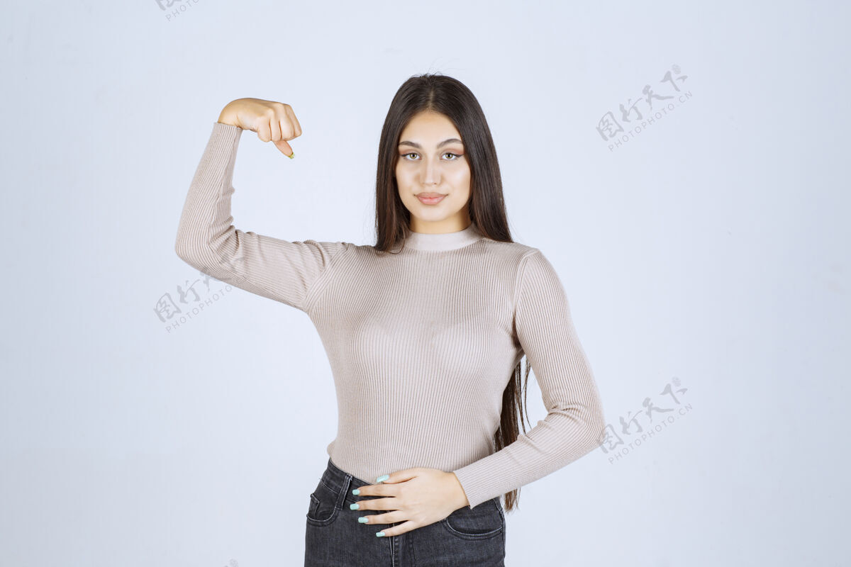 女性穿灰色毛衣的女孩展示她的拳头和力量力量成人员工