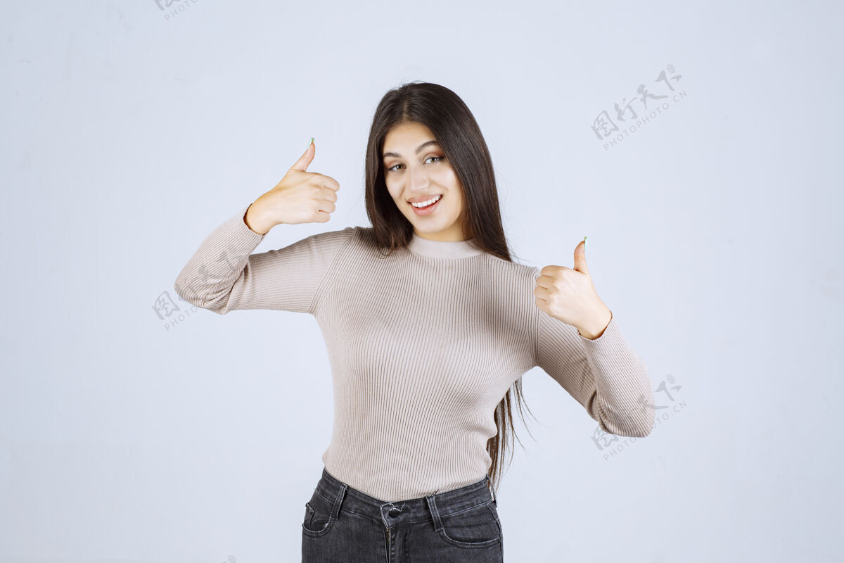 可以穿灰色衬衫的女孩在做竖起拇指的招牌年轻人女人工人