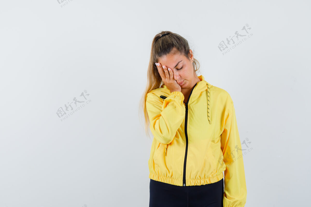 夹克金发女人用手捂住眼睛 穿着黄色棒球服和黑色裤子 看上去很烦躁成人裤子黑发