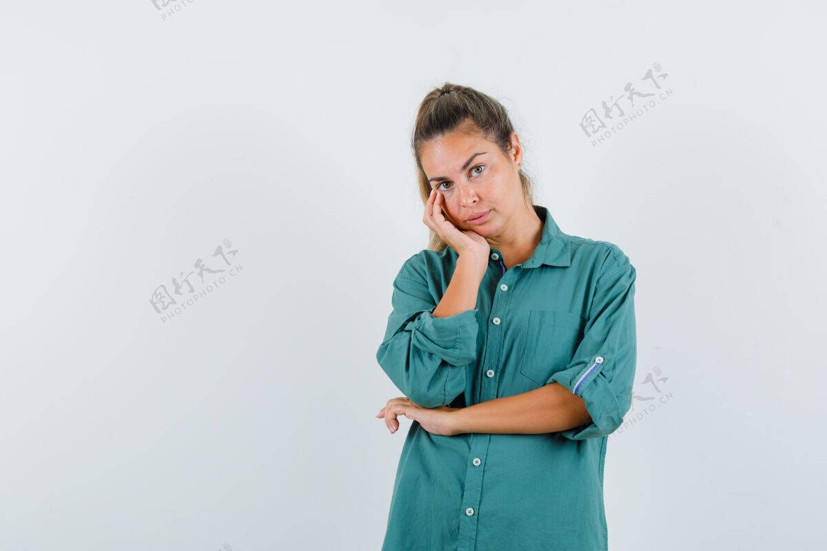 干净年轻女子面颊靠在手掌上 一边想着一件绿色衬衫 一边沉思着模特衬衫成人