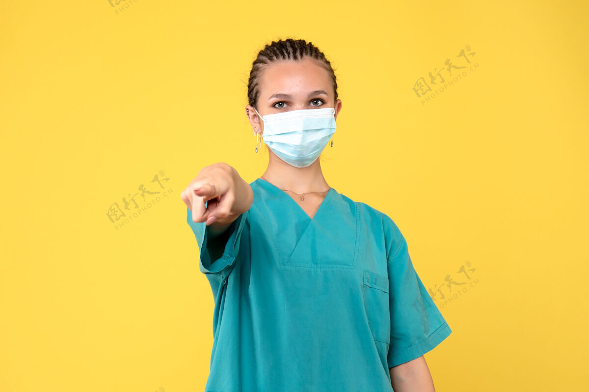 黄色正面图：身穿医用衬衫和面罩的女医生 健康护士医院 covid-19大流行医院手指指点