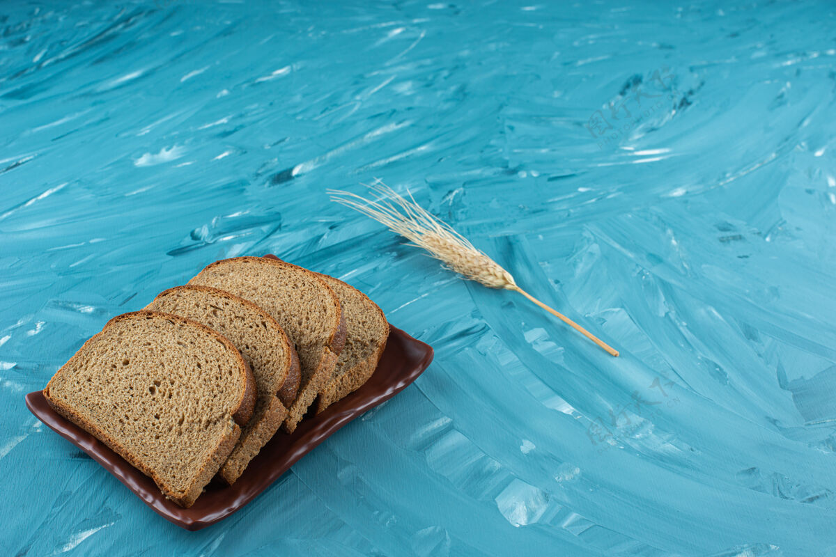 棕色一个棕色盘子 上面放着棕色切片面包和蓝色背景的耳朵晚餐好吃糕点