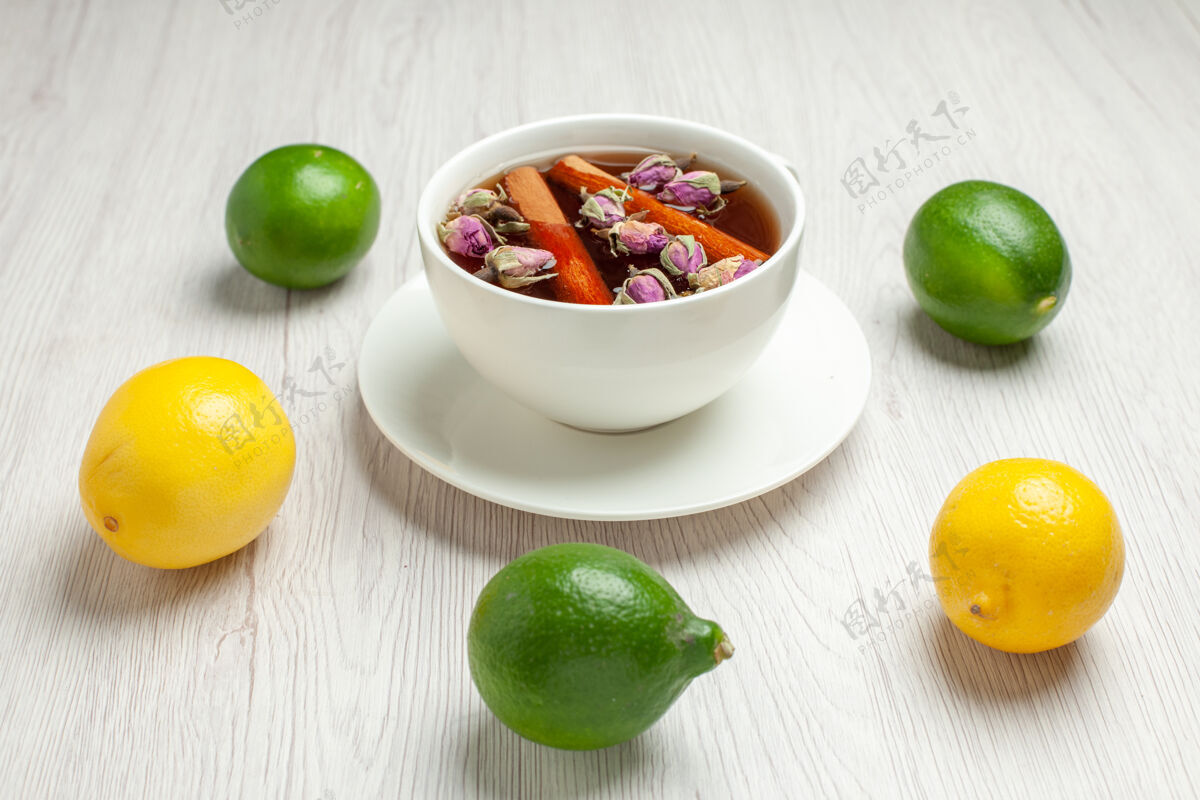 酸橙前视一杯茶 用新鲜柠檬放在白色书桌上 茶果呈柑橘色正面新鲜茶