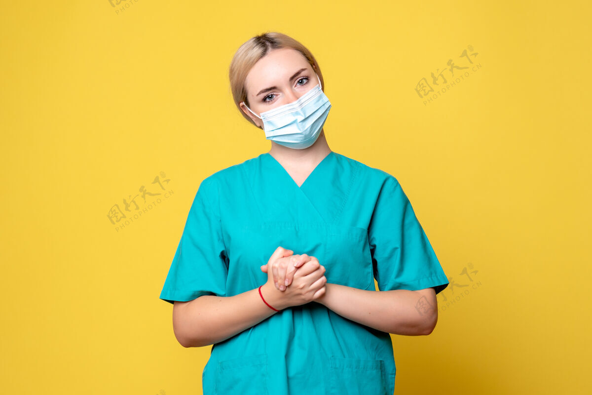 人物黄色墙壁上穿着医用衬衫和面罩的年轻女医生的正视图衬衫人物护士