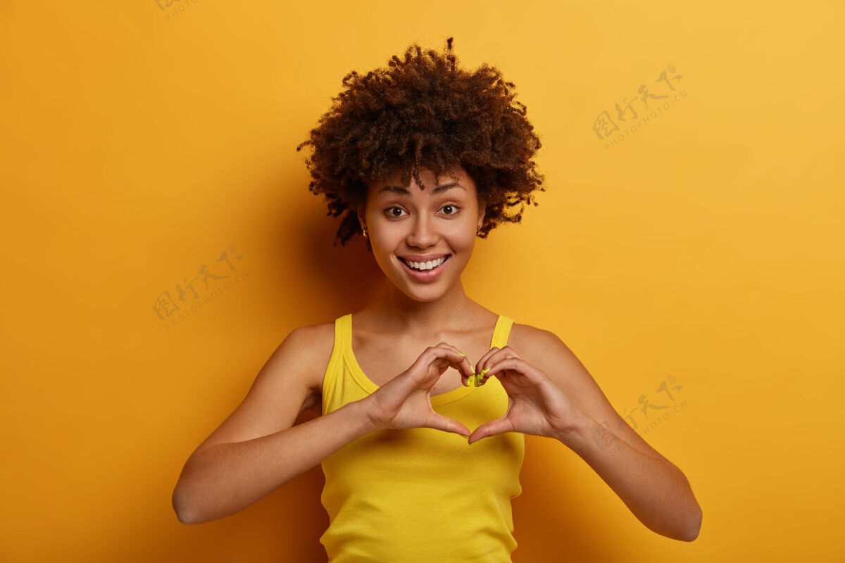 休闲美女画像做心形 说是我的情人 积极微笑 表达爱意和关怀 爱上一个人 穿黄色衬衫 独自站在室内情人节人类生活方式