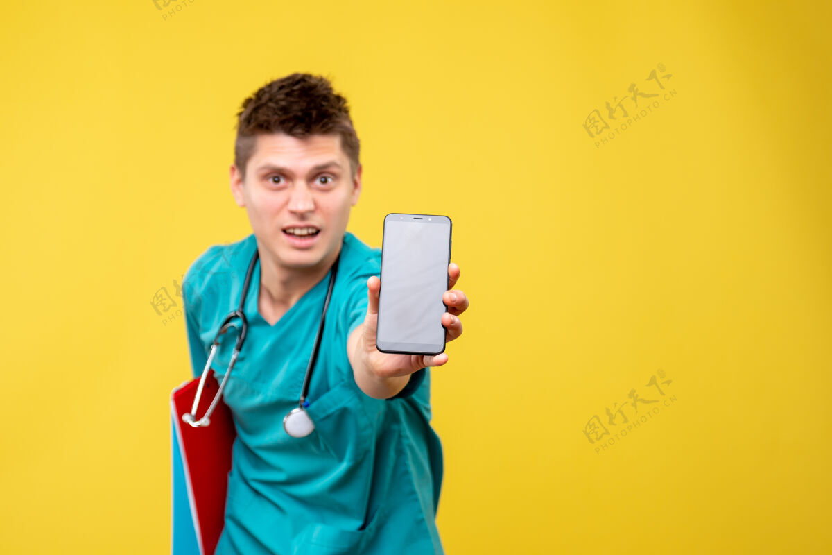 套装身穿医疗服的男医生正面图 黄色墙上有电话和便条男医生正面医院