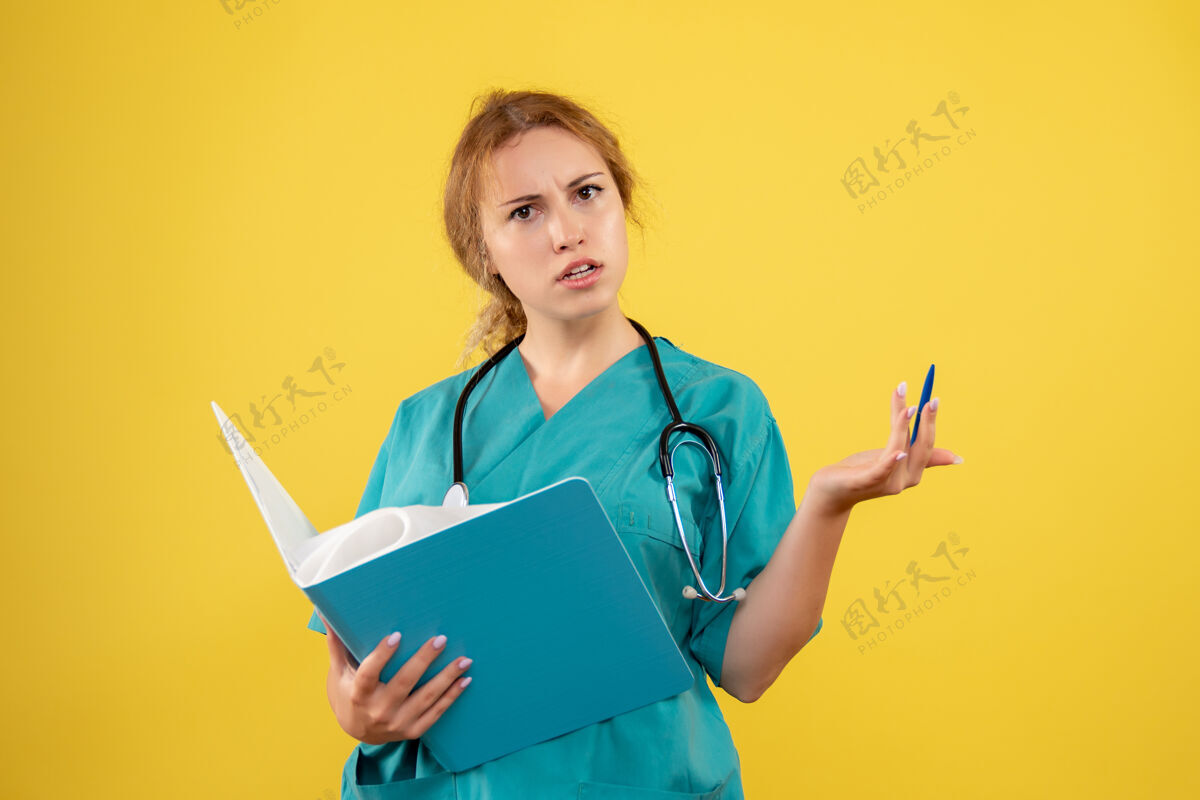 听诊器黄色墙壁上穿着医疗服的女医生的正视图病毒医生健康