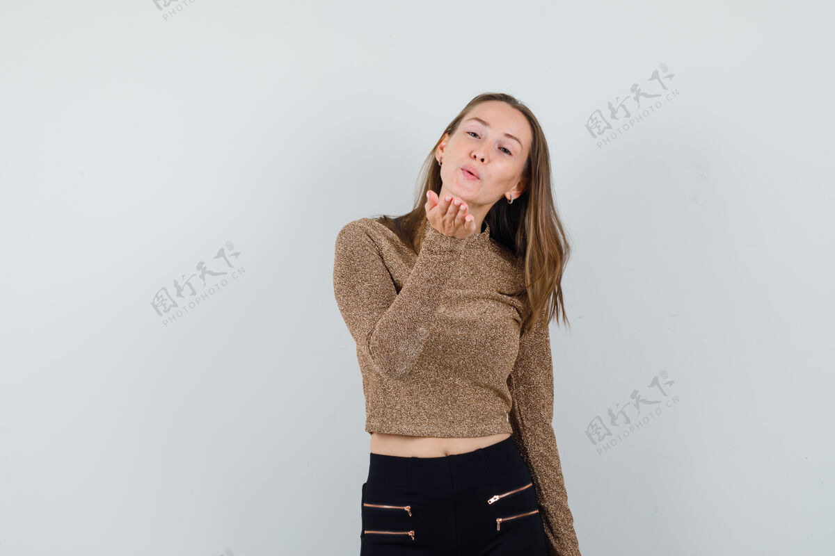 前面一个年轻的女人穿着金色的毛衣和黑色的裤子在前面送吻 看起来很开心护理女性女人