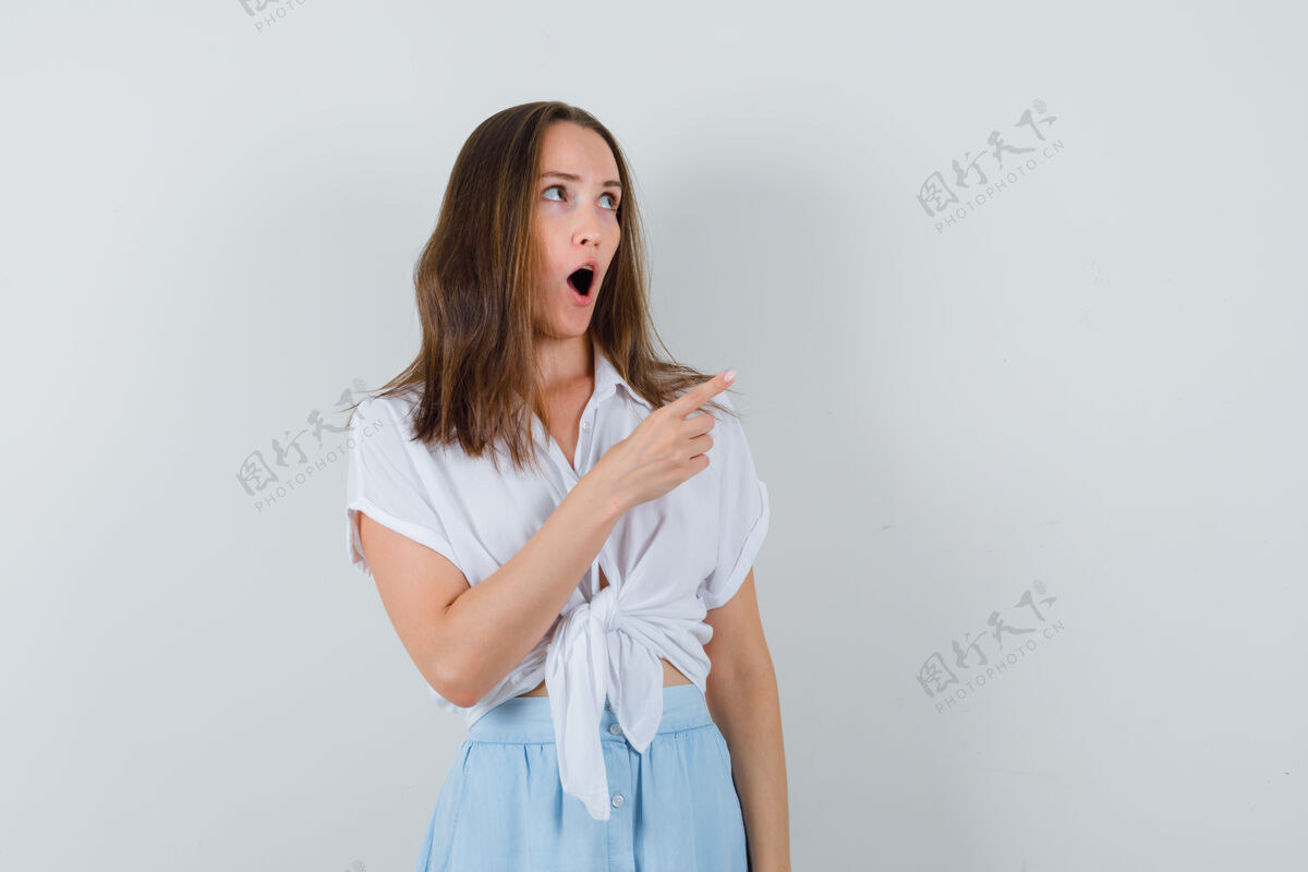 感性年轻的女士指着旁边的衬衫 裙子 看起来目瞪口呆年轻时尚头发
