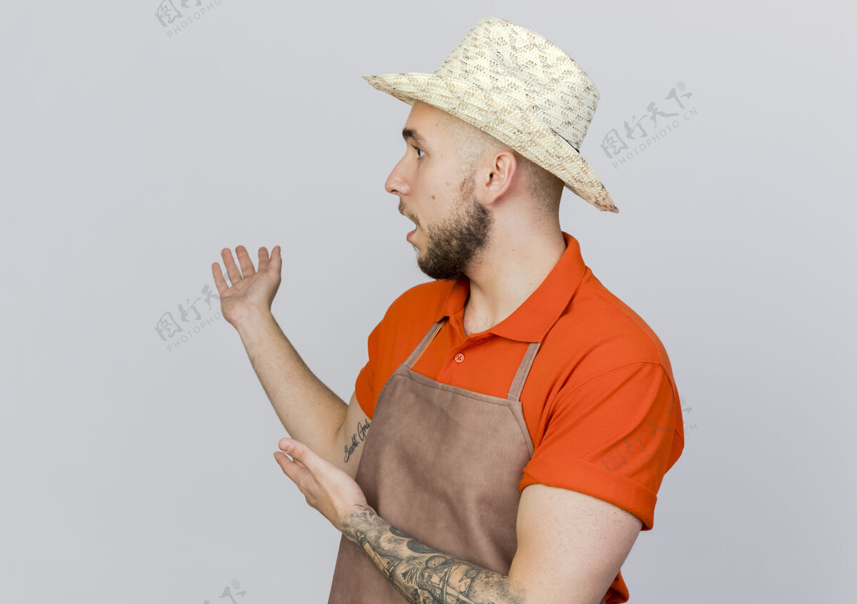 男震惊的男园丁戴着园艺帽点着身后 两手看着一旁园艺点壁板