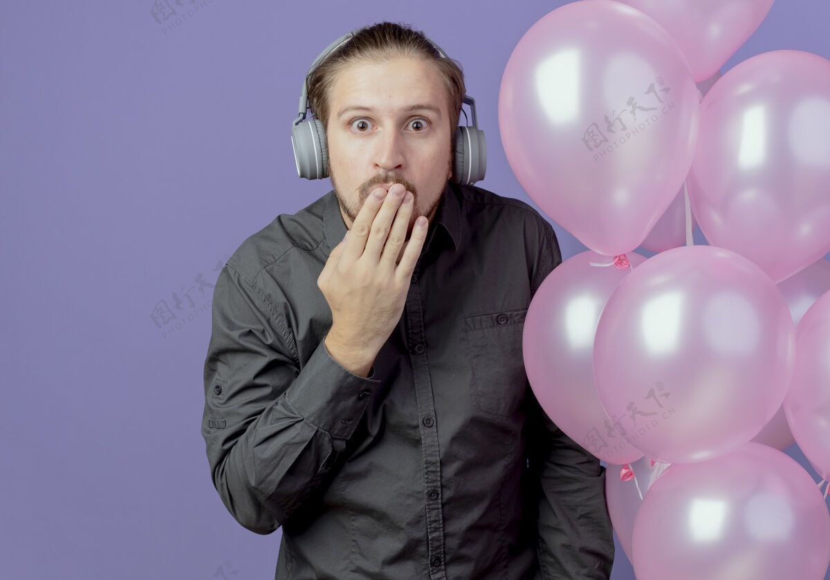 气球戴着耳机的帅哥站在那里 手放着氦气球 嘴被隔离在紫色的墙上紫色帅哥耳机