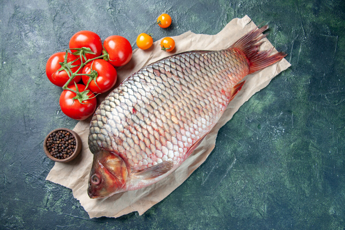 海鲜顶视图新鲜的生鱼肉和深蓝色背景上的红色西红柿风景番茄红