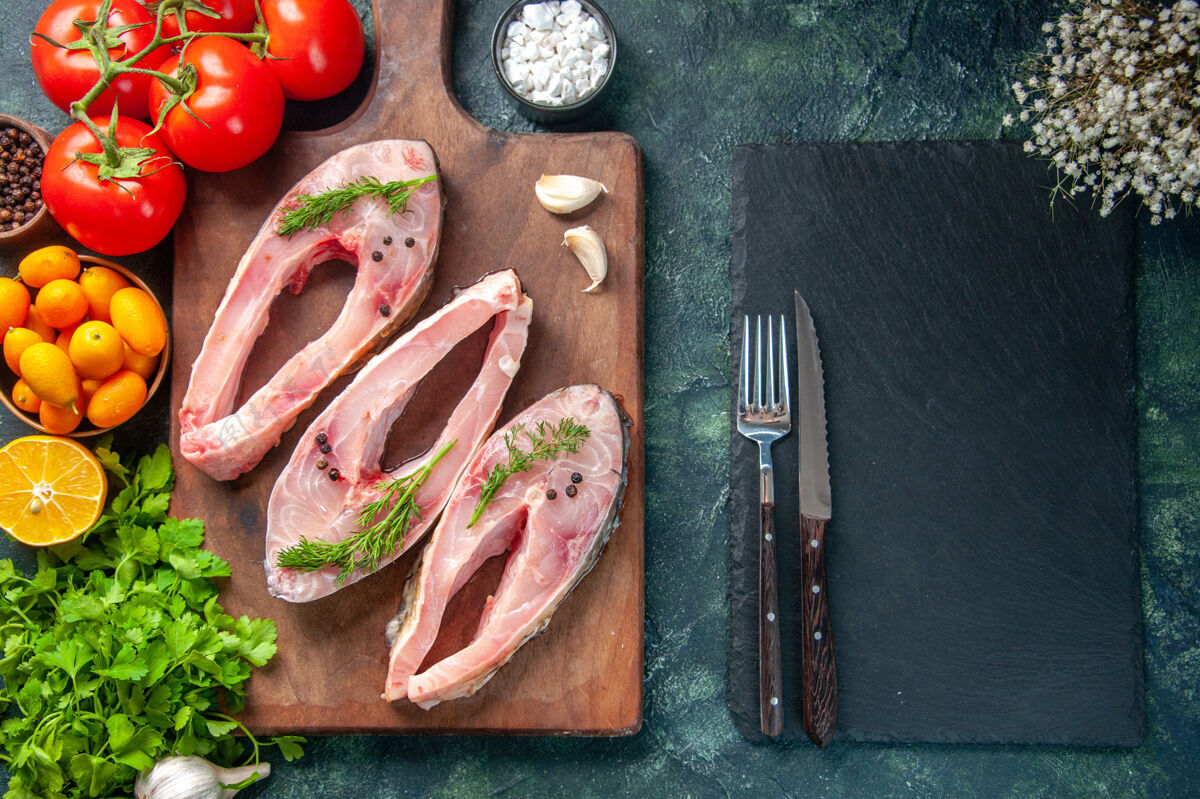食物顶视图新鲜鱼片与绿色和西红柿在黑暗的背景盘子饮食西红柿