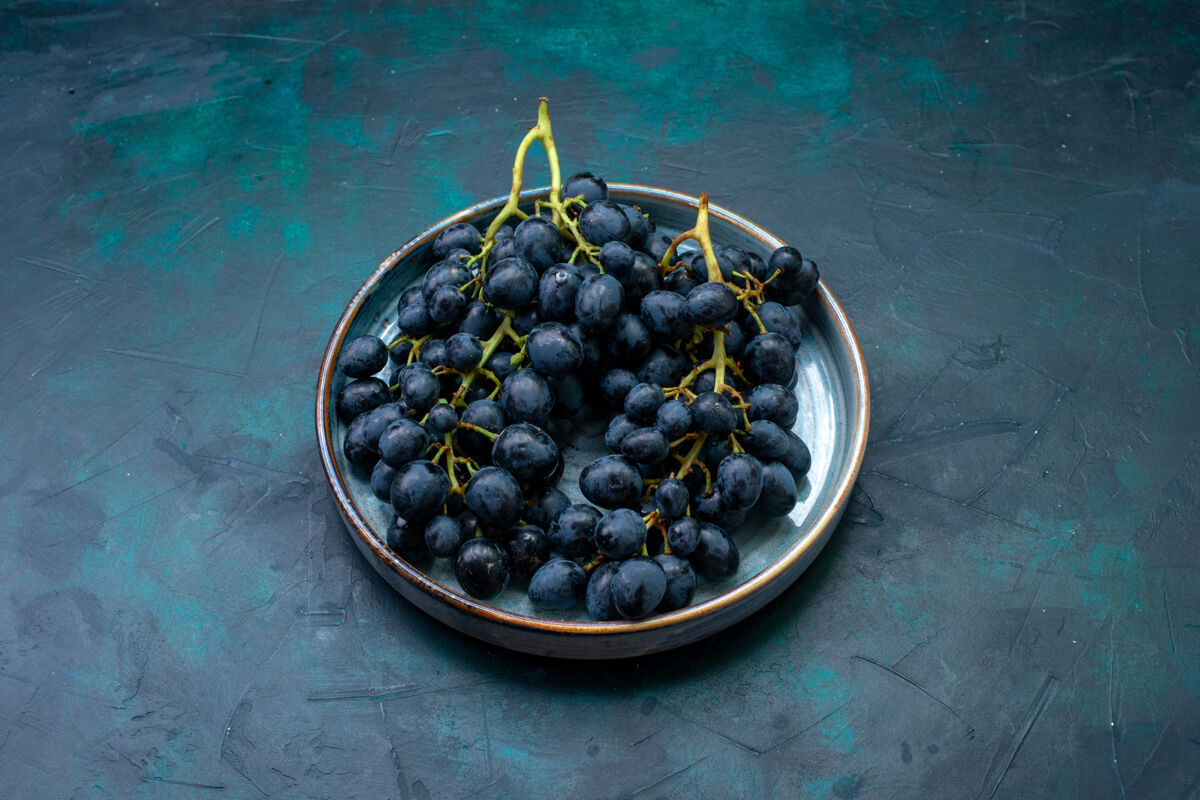 桌子前视图新鲜葡萄黑葡萄在黑暗的桌子上盘子葡萄深色
