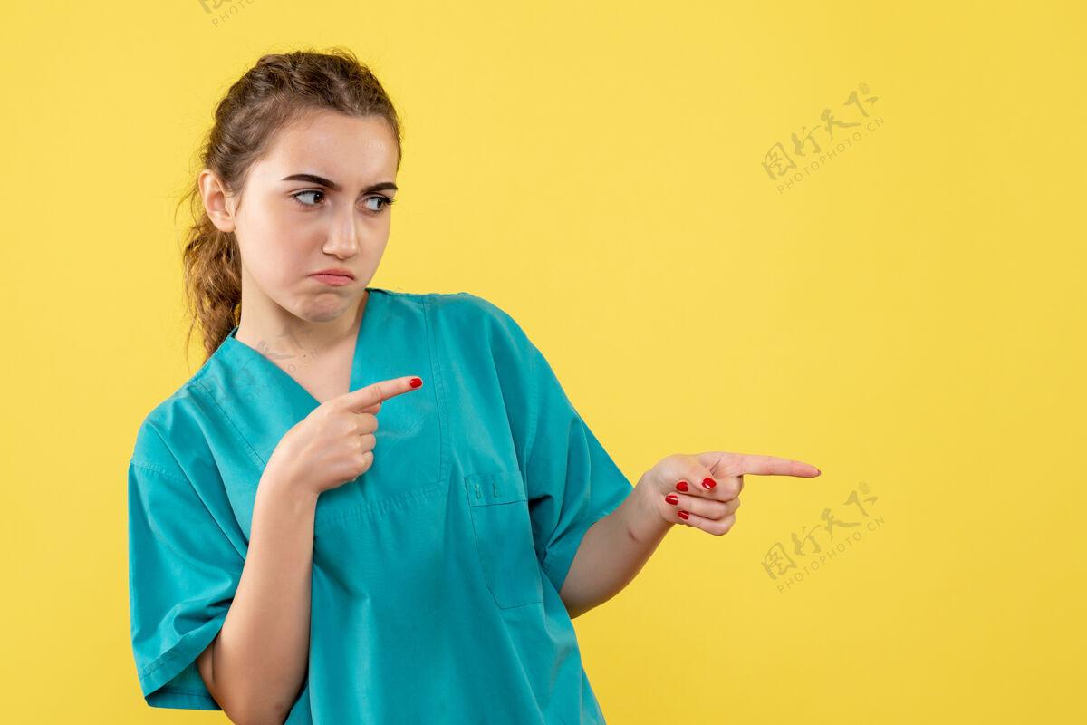 人黄色墙壁上穿着医疗服悲伤的女医生的正视图医院流行病成人