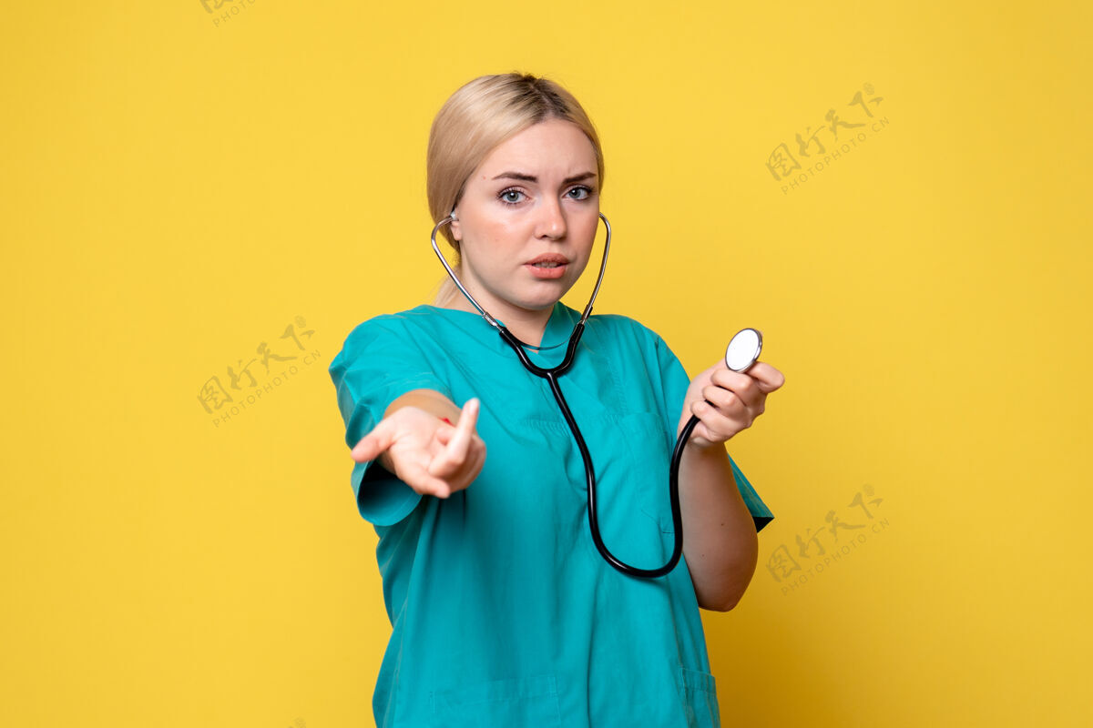 医疗黄色墙壁上穿着带听诊器的医用衬衫的女医生的正视图正面医疗器械听诊器