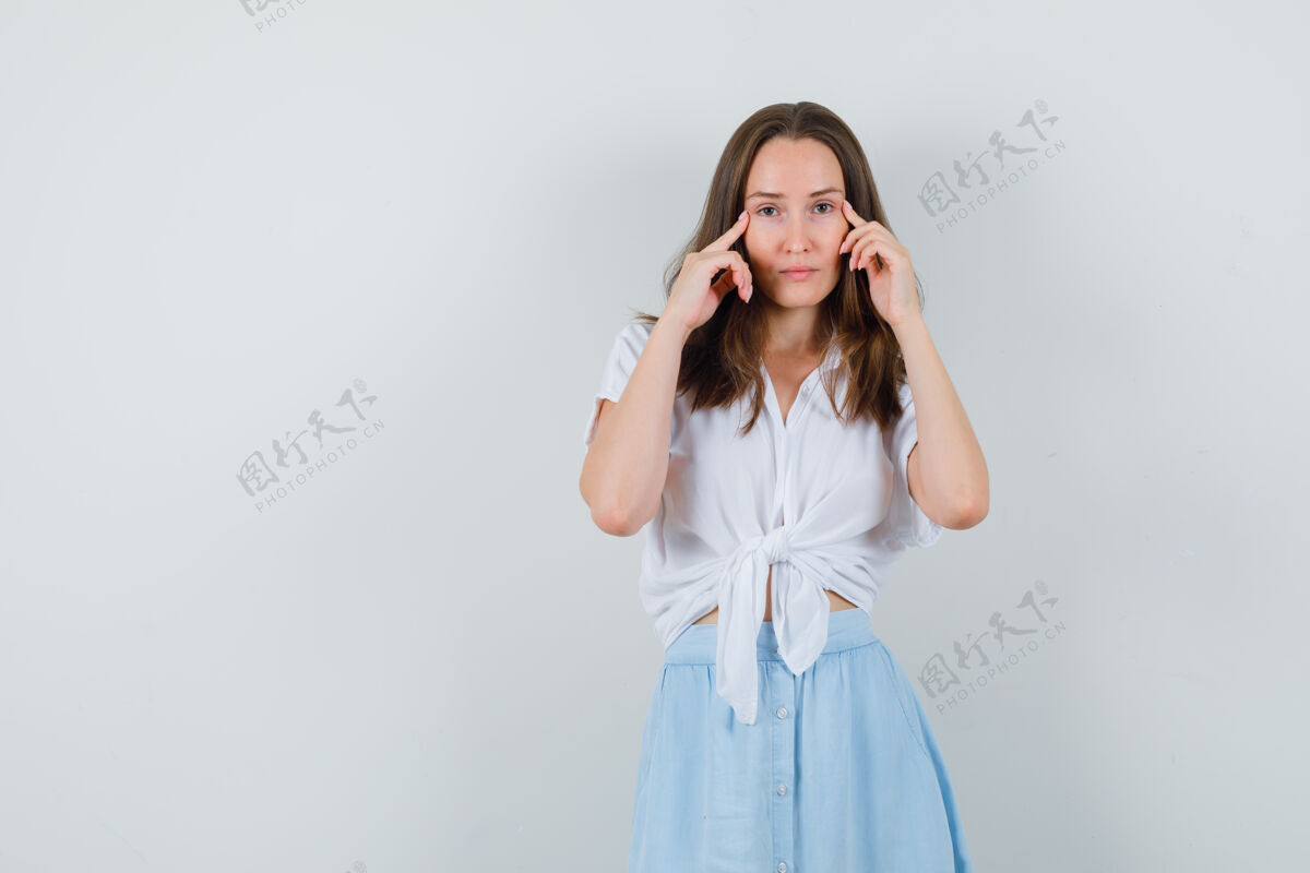 人一位穿着衬衫和裙子的年轻女士 手指放在太阳穴上 看起来很懂事护理健康女士