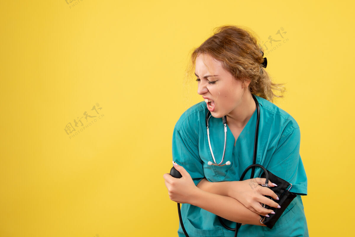 医疗器械身穿医疗服的女医生在黄色墙壁上检查压力的正视图检查健康女医生