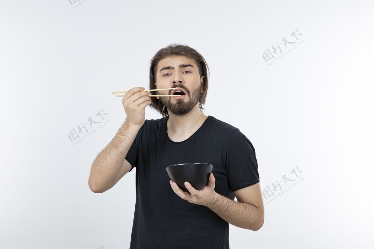 人一个留胡子的男人拿着筷子在白色的墙上拿着碗小伙子摆姿势男性