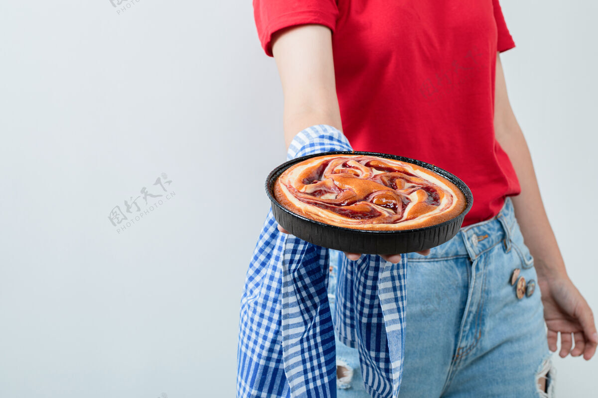 模特穿红衬衫的年轻女孩手里拿着一个黑平底锅里的馅饼年轻女士休闲