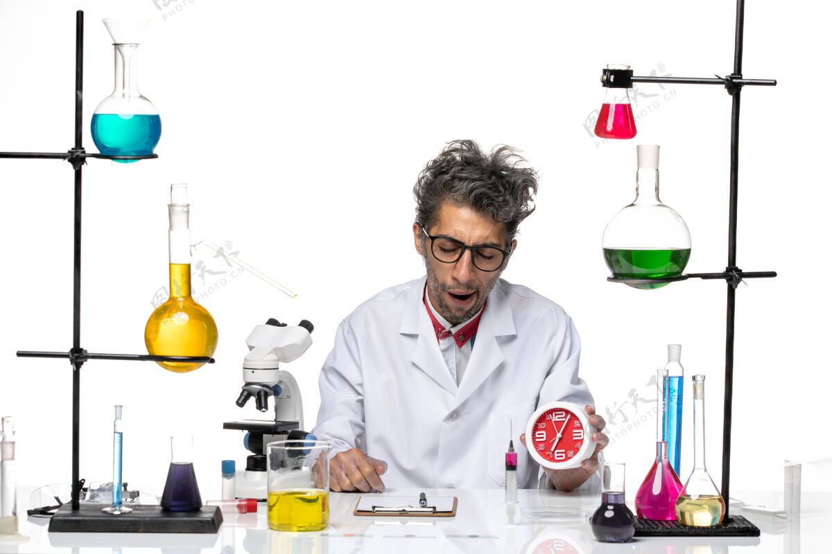 医院前视图身穿医疗服的男科学家手持浅白色背景上的时钟化学健康冠状病毒-实验室病毒化学成人人
