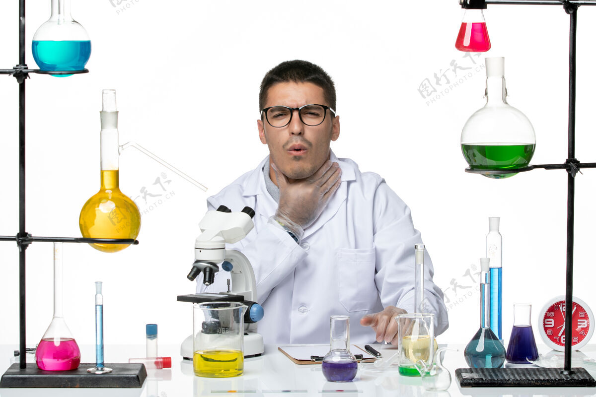 外套正面图：身穿白色医疗服的男性化学家坐在白色背景病毒实验室冠状病毒-疾病科学的解决方案喉咙痛烧杯疼痛喉咙