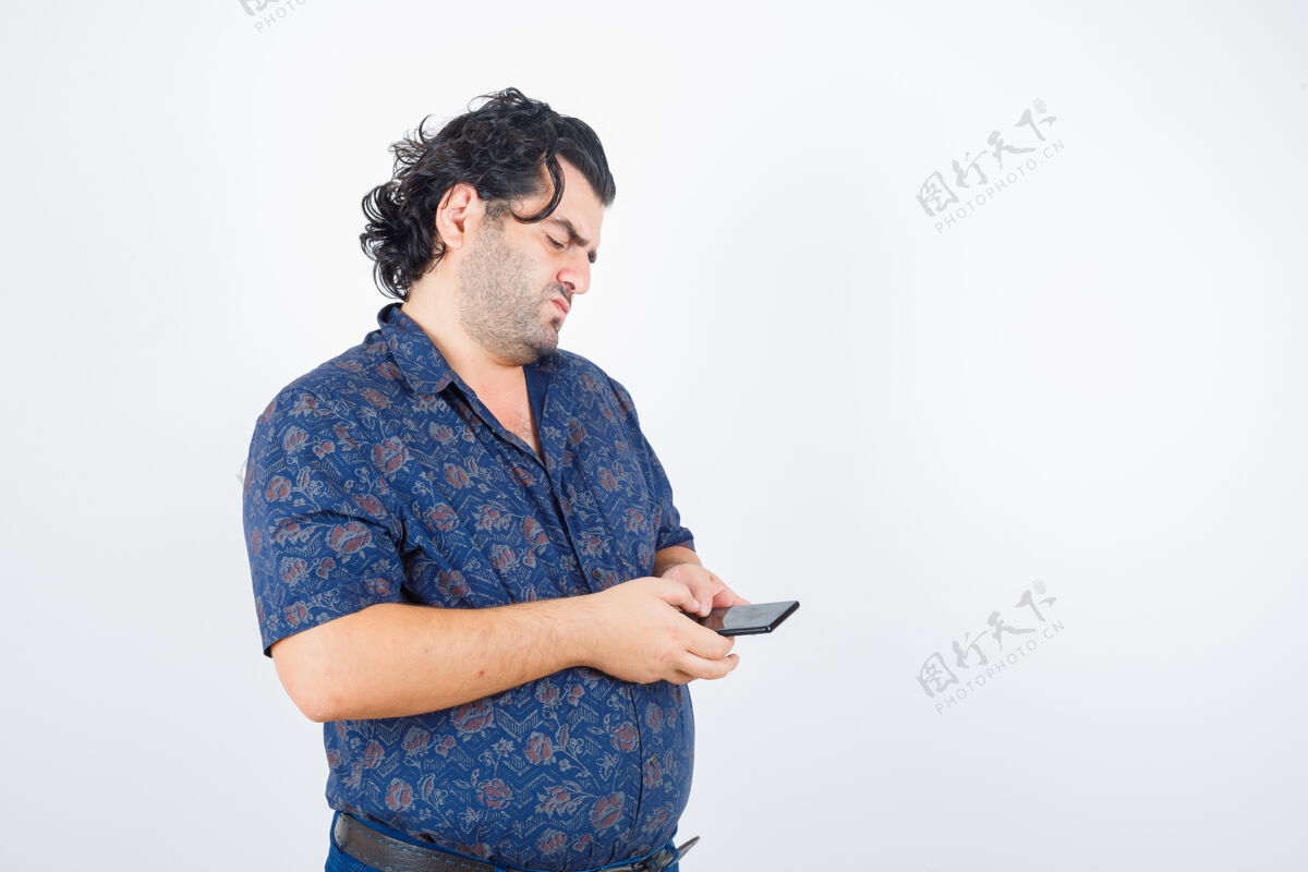 电话成熟的男人看着穿着衬衫的手机 若有所思地看着 眼前一亮英俊老肖像