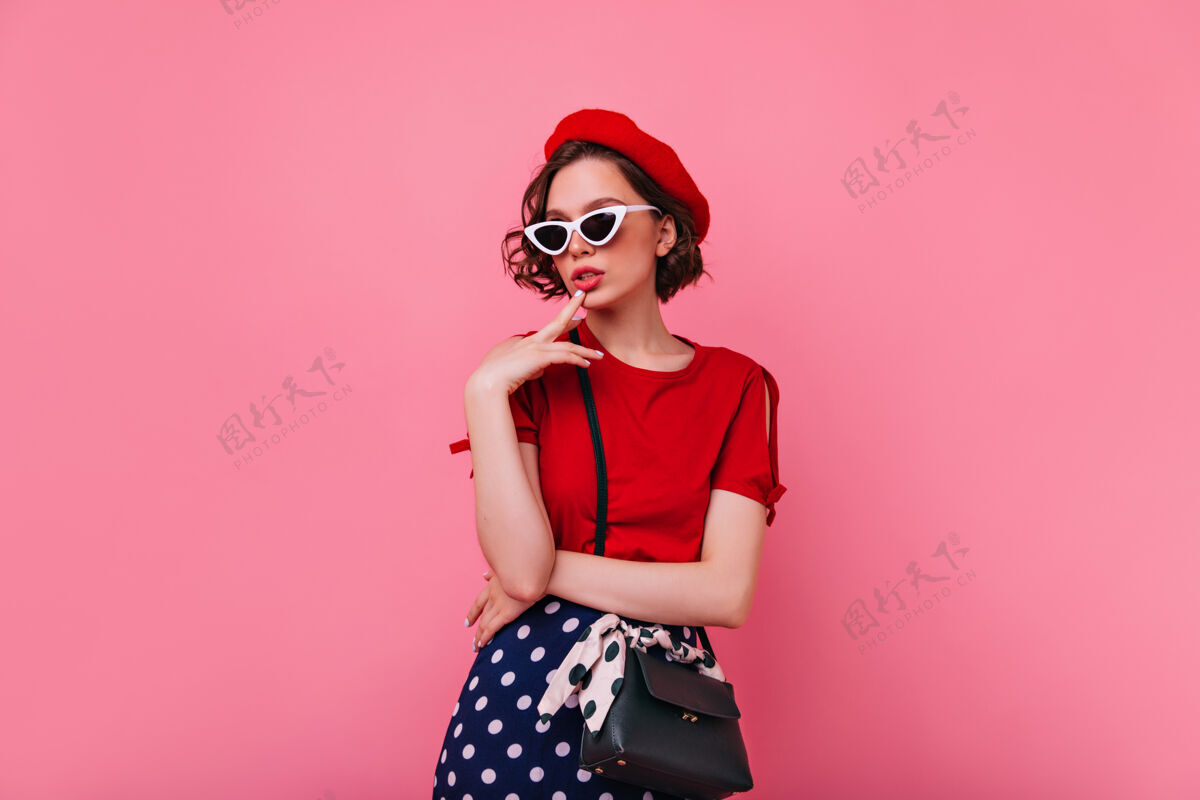 女性狂喜的法国女士留着短发摆姿势自信的欧洲女模特穿着红色t恤站着室内休息女人