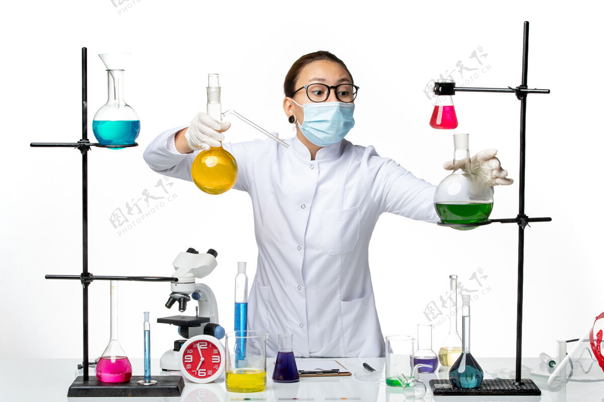 医学前视图：身穿医疗服的女化学家 戴着面罩 在白色背景病毒化学实验室的covidsplash上处理溶液化学实验室前面