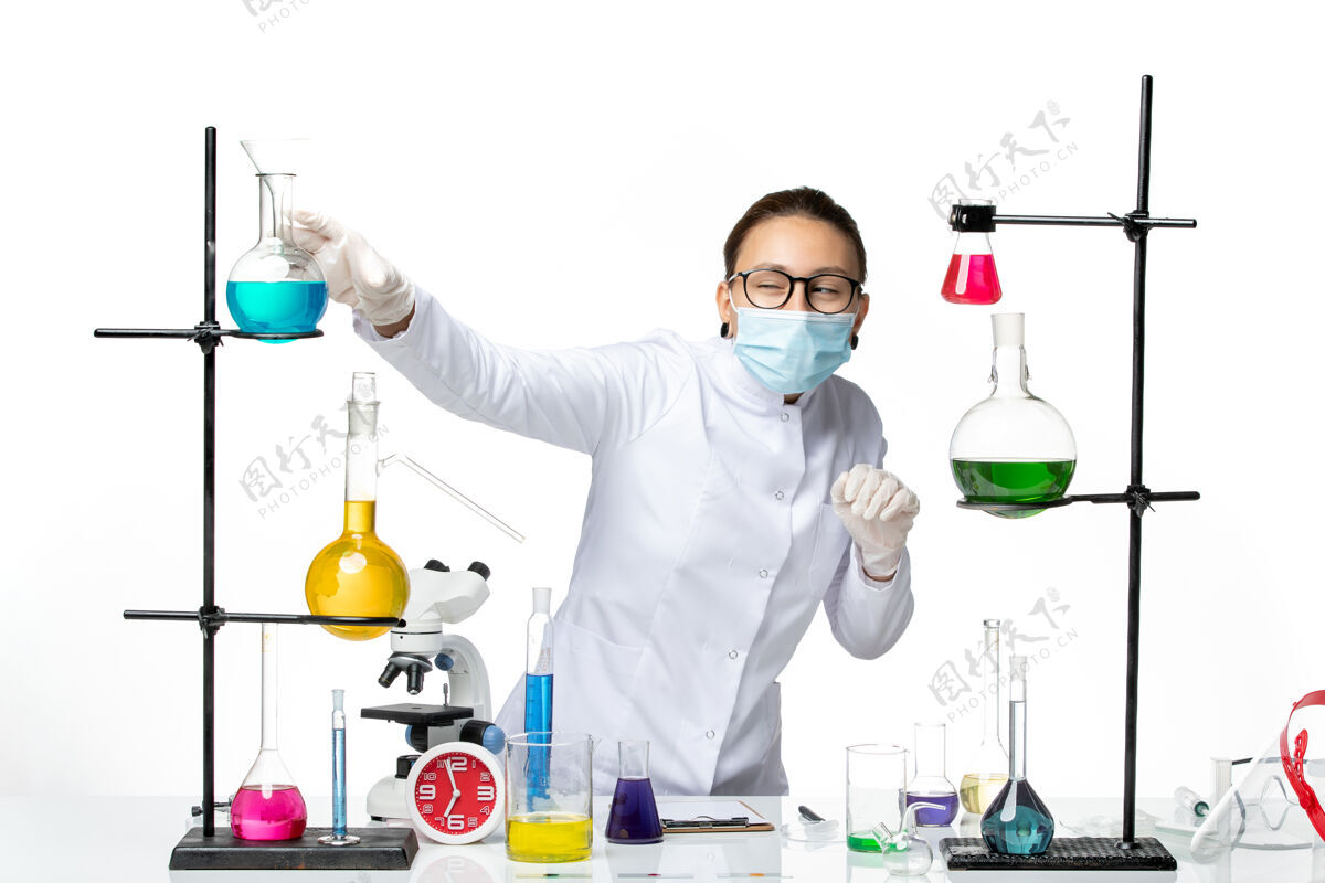 研究前视图穿着医疗服的女化学家 带着面具 在白色背景上混合溶液病毒化学实验室covidsplash正面喷溅溶液