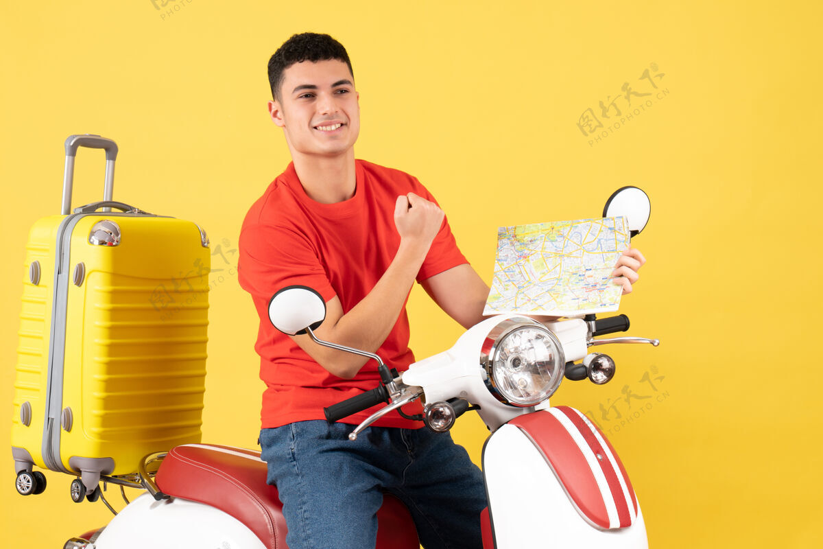 持有前视图快乐的帅哥骑着轻便摩托车拿着地图人地图运动