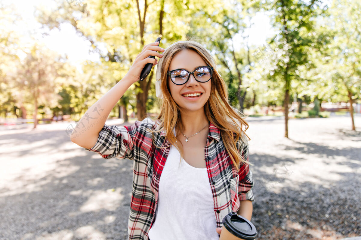 现代戴着闪亮眼镜的快乐白人女孩在公园里度过时光可爱的金发女模特在享受春天的周末欧洲放松欢笑