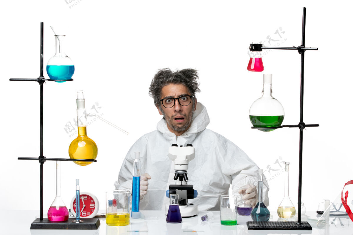 药品前视图穿着特殊防护服的疯狂男科学家围坐在桌子旁 用白色办公桌上的疾病病毒解决实验室科学病毒特殊科学西装