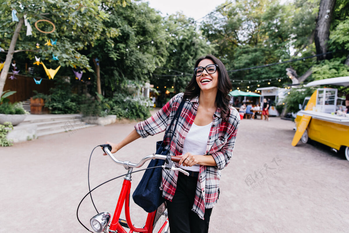 夏天穿着休闲装的漂亮女孩在春天享受着积极的休闲戴眼镜的拉丁女模特骑着自行车站在街上女性模型漂亮