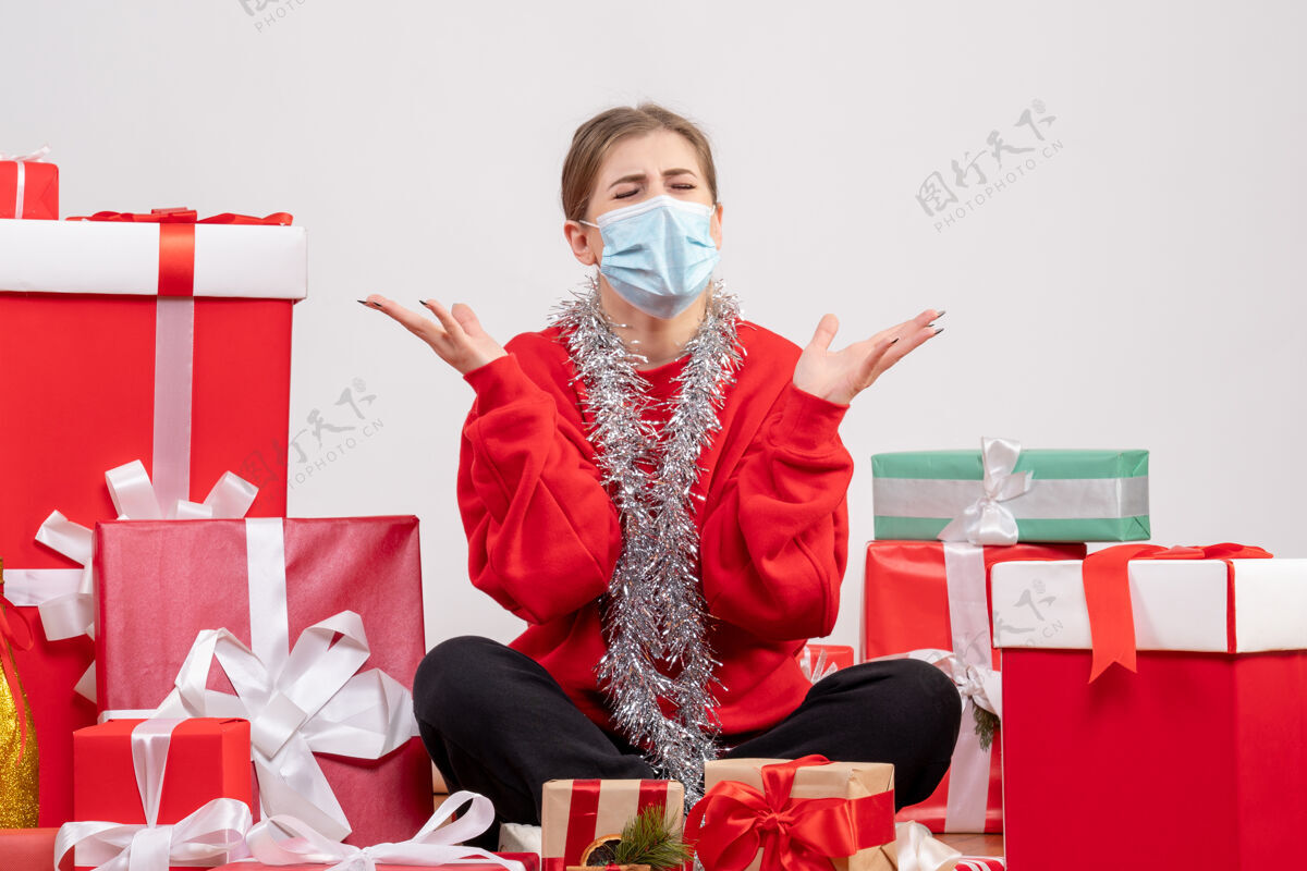 年份正面图：年轻女性戴着无菌面具坐着 手里拿着圣诞礼物年轻女性健康情绪