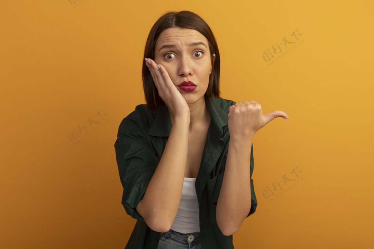 姿势焦虑的白种美女把手放在脸上 指着橙色的边点黑发女人