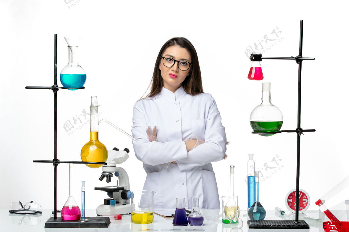 前面正面图：穿着无菌医疗服的女化学家站在桌子旁 拿着白色背景病毒疾病的解决方案-实验室科学烧杯医生疾病