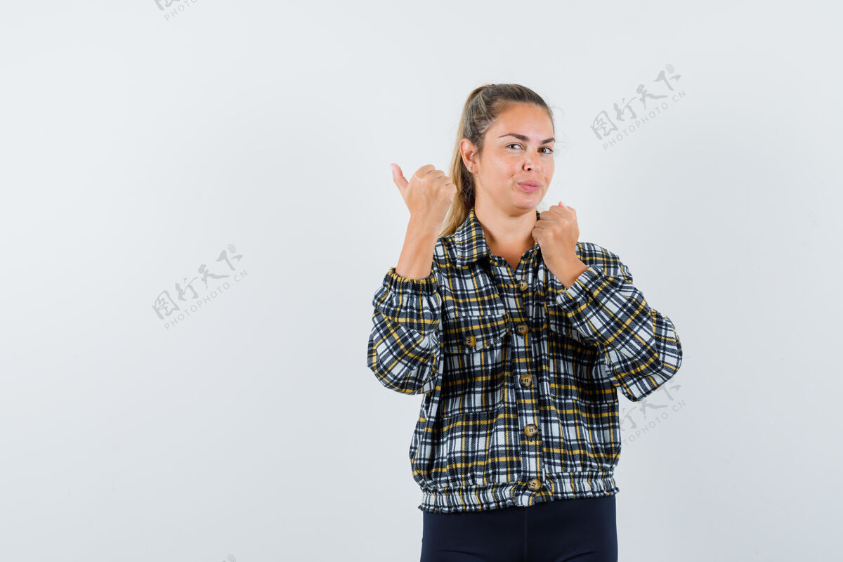 脸年轻女性用拇指指着衬衫 短裤 看起来很自信正面视图一个拇指肖像